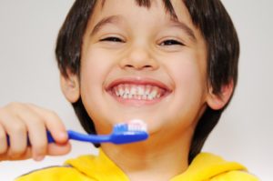 kid brushing teeth smiling