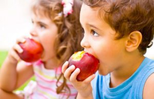 two kids eating apples
