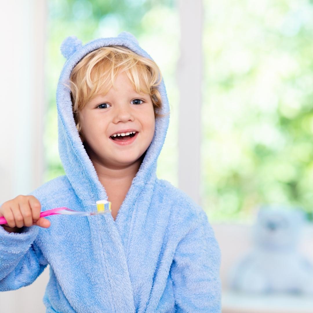 boy in a teddy bear bathrobe brushing teeth